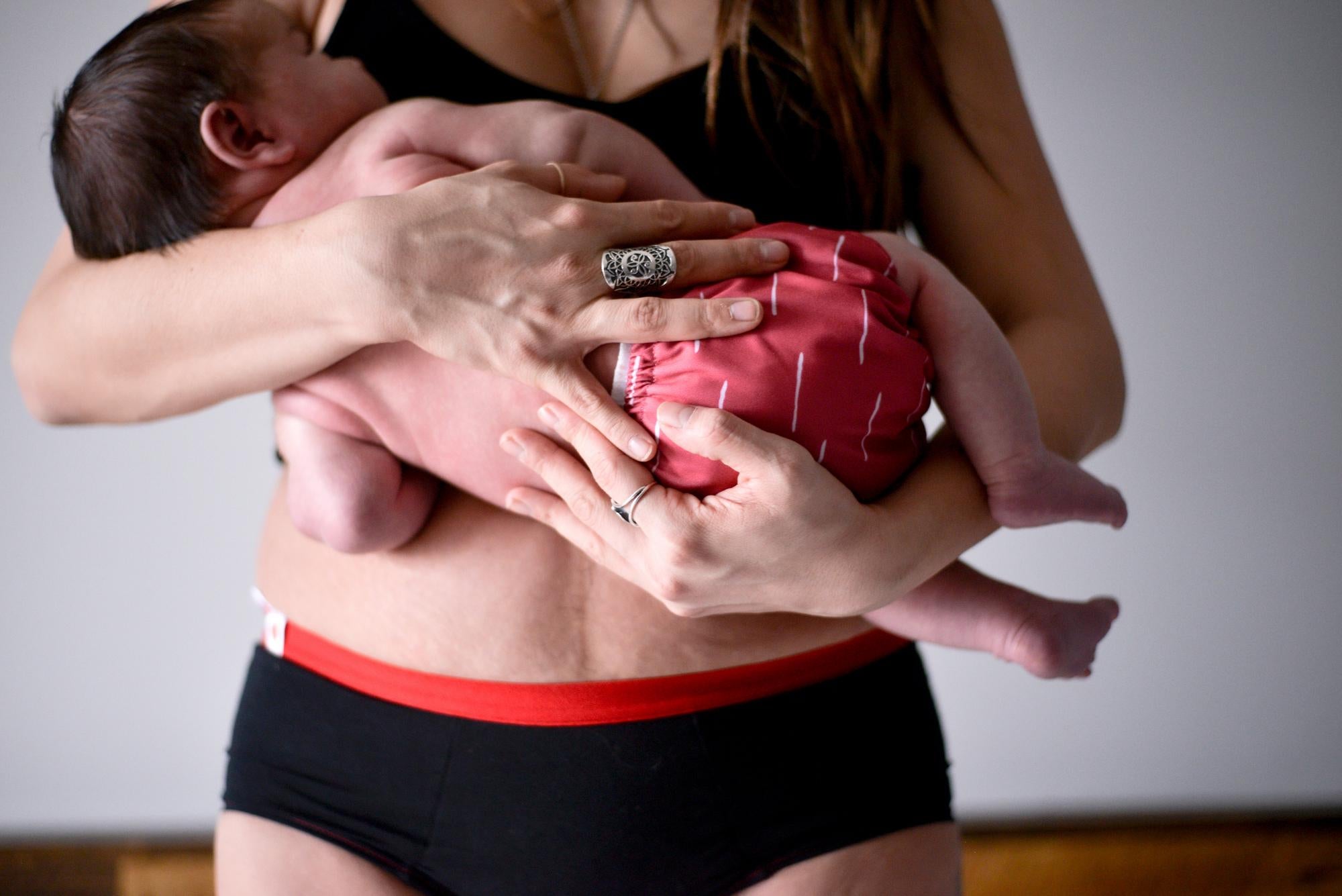 Une femme en période postpartum tient son nouveau-né dans ses bras.